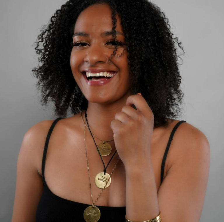Smiling woman wearing gold pendants from Raha by Lilian