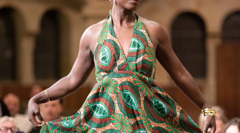 Model in a green and yellow print dress on the runway at the Black Essence Fashion Show in Basel