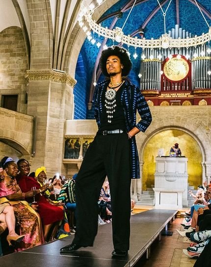 Model in a navy patterned jacket and black trousers on the Black Essence runway